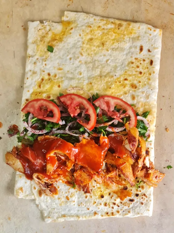 Açık lavaş üzerinde tavuk döner, sos, domates ve sumaklı soğan piyazı