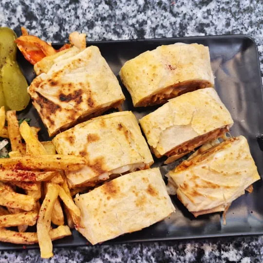 Tabakta dilimlenmiş kaşarlı lavaş döner ve patates kızartması